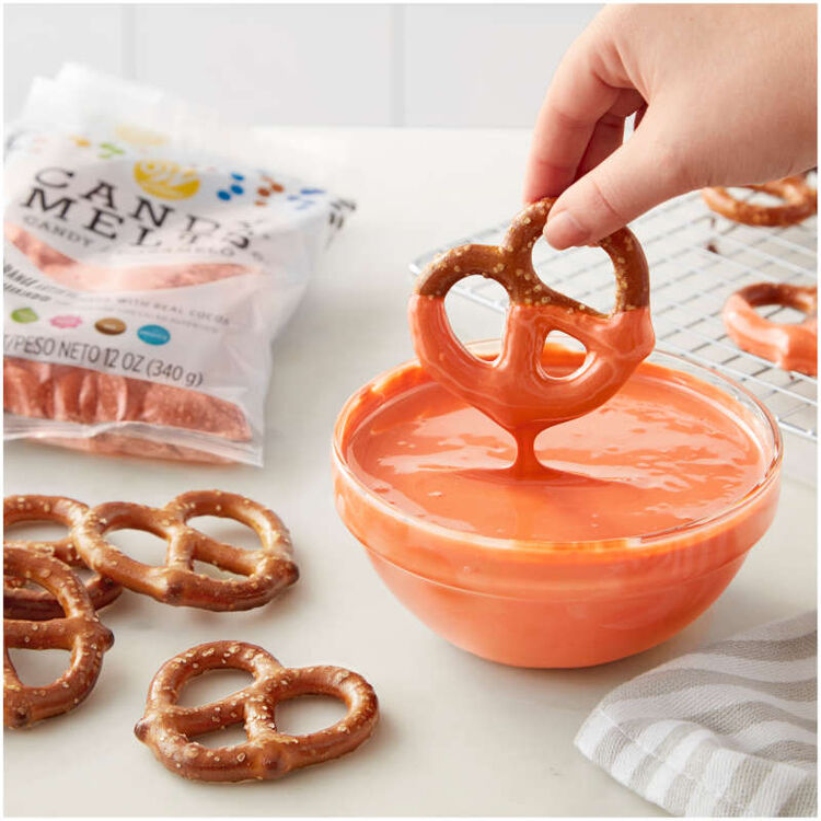 Dipping Pretzels into bowl of melted orange Candy Melts Candy