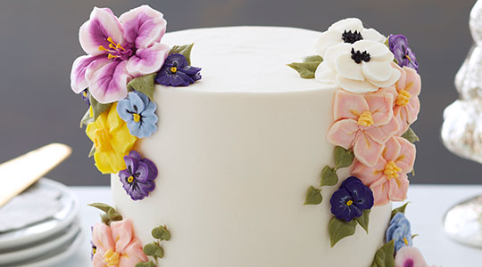 Fall buttercream flowers on top of a white and navy striped cake